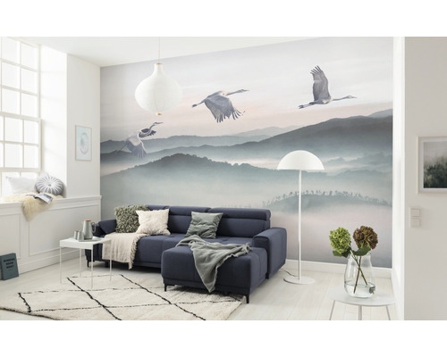 Woonkamer met fotobehang berglandschap en kraanvogels, bank, tapijt en decoratie.