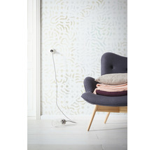 Scène met een behang met patroon, een fauteuil met kussens en decoraties en een lamp op de vloer.