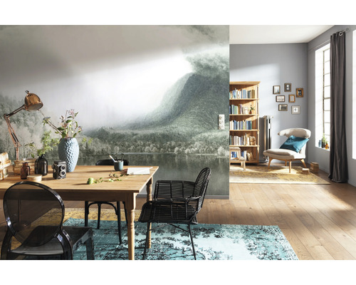 Woonkamer met fotobehang berglandschap, houten tafel, stoelen en boekenrek