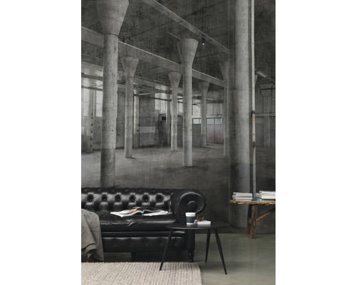 Woonkamer met zwarte leren bank voor een fotobehang met een fabriekshalmotief