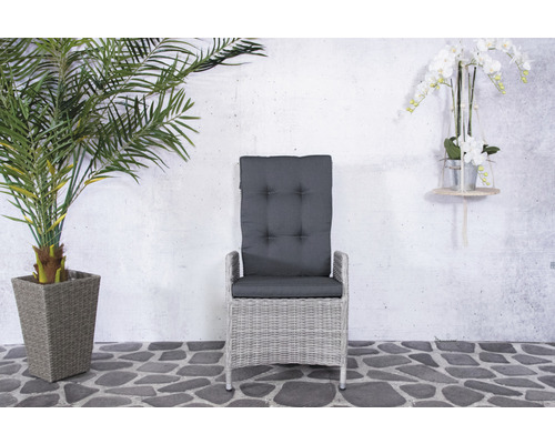 Tuinstoel van rotan met grijze kussens voor een grijze muur