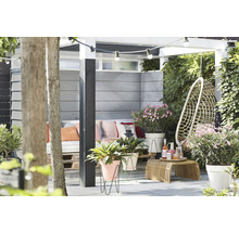 Gedecoreerde tuin met zitje, hangstoel, bijzettafel, planten en lichtslinger.