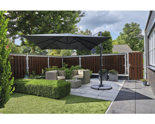 Vierkante parasol boven een zithoek in de tuin.