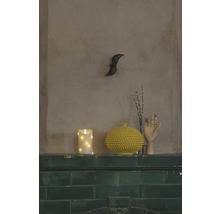 Decoratieve opstelling met kaars, vaas, houten hand en takken op een schoorsteenmantel.