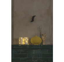 Decoratieve opstelling met kaarsen, vaas en houten hand op een groene plank