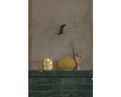 Decoratieve scène met ledkaars, stekelige vaas en houten hand op een groene tegelschouw.