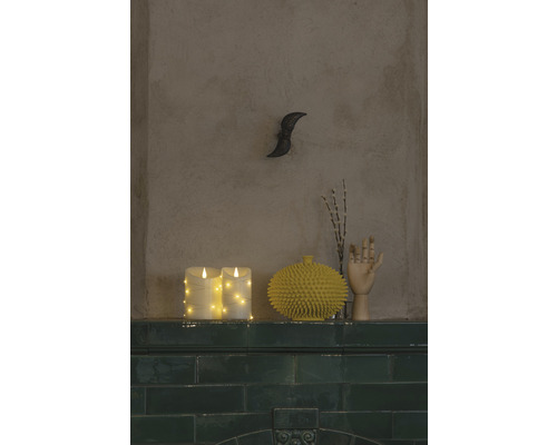 Decoratieve scène met LED kaarsen, een gele vaas, een houten handmodel en een wanddecoratie op een plank.