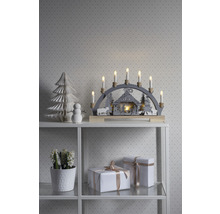 Kerstdecoratie met lichtboog, papieren boom, sneeuwpop en geschenken op een plank