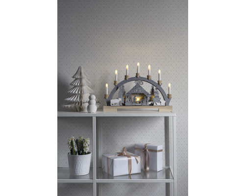 Kerstdecoratie met lichtboog, papieren boom, sneeuwpop en geschenken op een plank