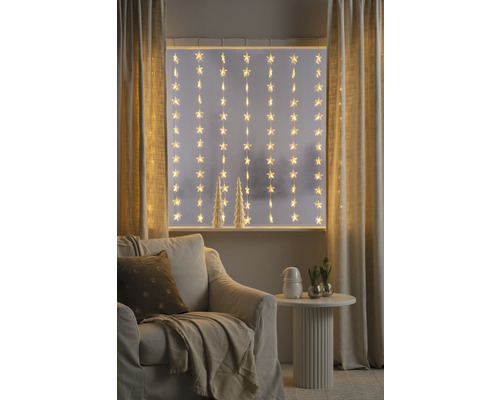 Decoratieve woonkamer met sterrenlichtjes voor het raam, fauteuil en bijzettafel