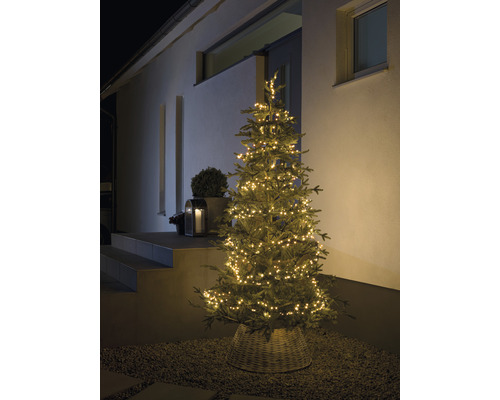 Verlichte kerstboom buiten voor een huis.