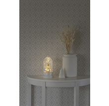 Decoratieve sneeuwbol met kerstboommotief op een tafel