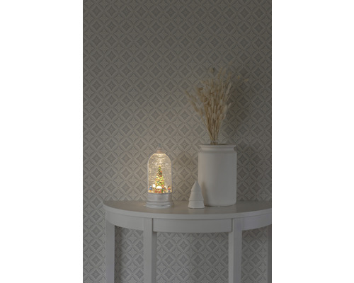 Decoratieve sneeuwbol met kerstboommotief op een tafel