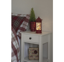 Nachtkastje met kerstdecoratie, inclusief een sneeuwbol met een kerstmanmotief en een potplant