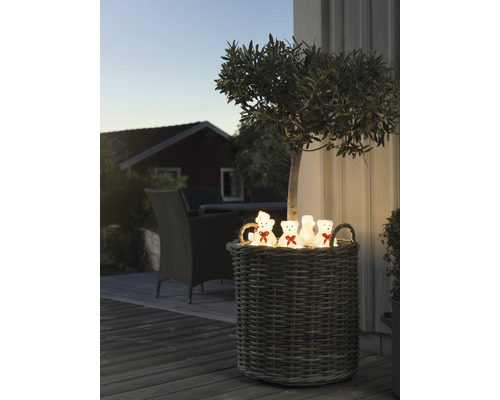 Decoratieve rieten mand met teddybeerlichtjes buiten.