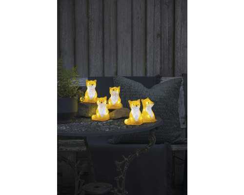 Decoratieve vosfiguren op een tuintafel met plant en kussens