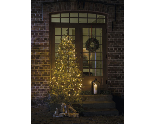 Versierde voordeur met verlichte kerstboom, adventskrans en lantaarn voor een feestelijke sfeer