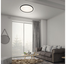 Woonkamer met een plafondlamp met ronde vorm, bank en gordijnen.