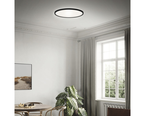 Een lichte ruimte met een ronde plafondlamp, een tafel en een raam.