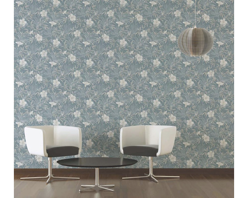 Een kamer met blauw behang met bloemmotief, twee stoelen en een tafel.