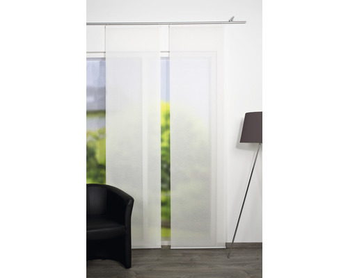 Twee witte schuifgordijnen met een fauteuil en een lamp in een kamer.