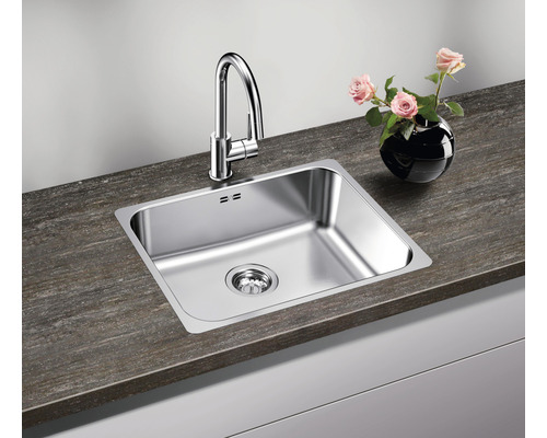 Spoelbak met kraan en afvoer op een aanrecht met een vaas bloemen