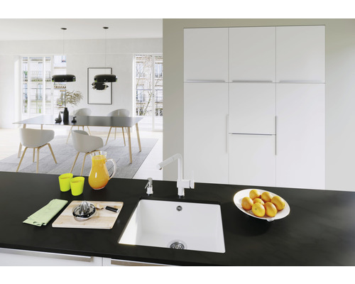 Lichte eetkamer met eettafel, stoelen, hanglampen en een spoelbak op een werkblad