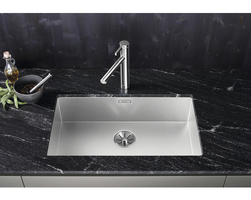 Roestvrijstalen spoelbak met kraan op een donker aanrechtblad