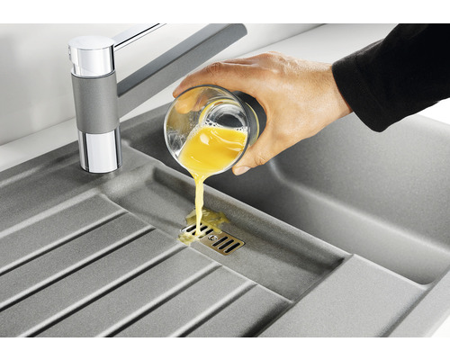 Spoelbak met kraan en hand die een glas vloeistof uitgiet