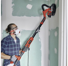 Man schuurt een muur met een langnekschuurmachine