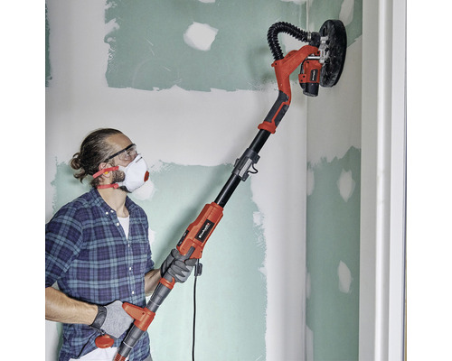 Man schuurt een muur met een langnekschuurmachine