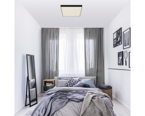 Slaapkamer met plafondlamp, bed, gordijnen en spiegel