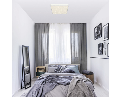 Slaapkamer met plafondlamp, bed, gordijnen en spiegel