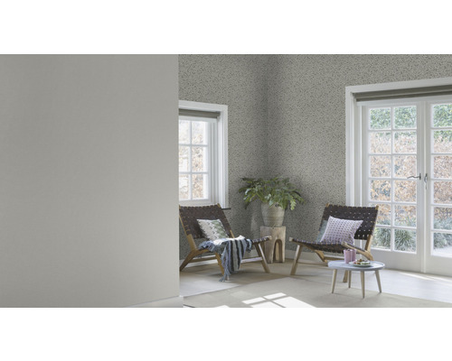 Lichte kamer met patroonbehang, twee houten stoelen en een kleine tafel