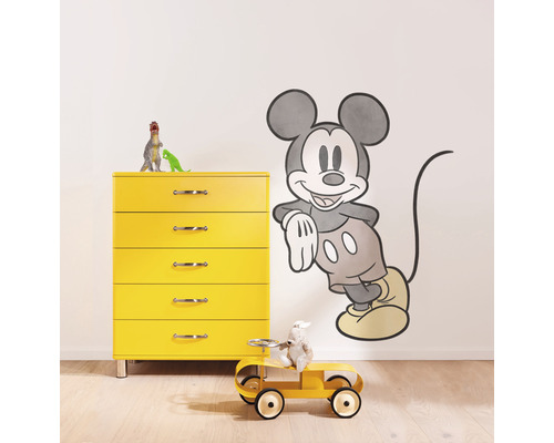 Scene met gele commode, speelgoedauto en Mickey Mouse muursticker