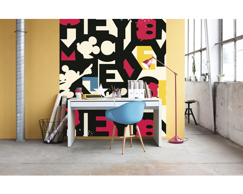 Een kamer met een bureau, een stoel en behang met een letterpatroon