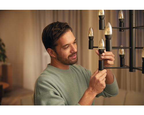 Man vervangt een LED lamp in een kroonluchter