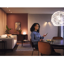 Woonkamer met verlichting, vrouw met smartphone aan de eettafel
