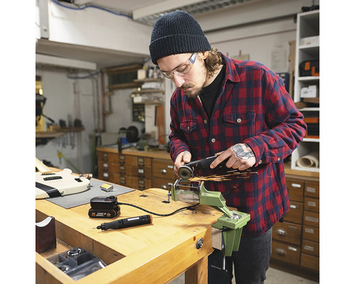 Man met veiligheidsbril bewerkt metaal met een haakse slijper in een werkplaats.