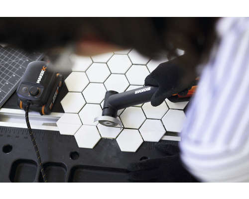 Tegelsnijder die zeshoekige tegels snijdt op een werkbank, aangedreven door Maker X hub en Worx logo.