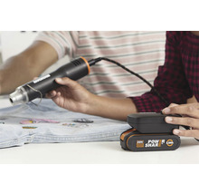 Heteluchtpistool met batterij in gebruik bij het aanbrengen van patches op een spijkerjas