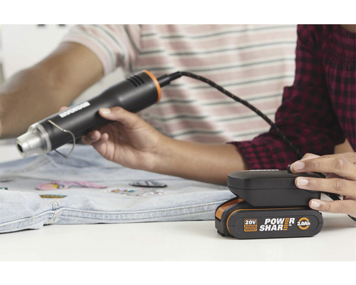 Heteluchtpistool met batterij in gebruik bij het aanbrengen van patches op een spijkerjas
