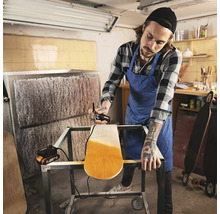 Man schildert een skateboard met een verfspuitpistool in een werkplaats.