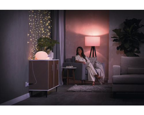 Woonkamer met verlichting, commode, bank en vrouw