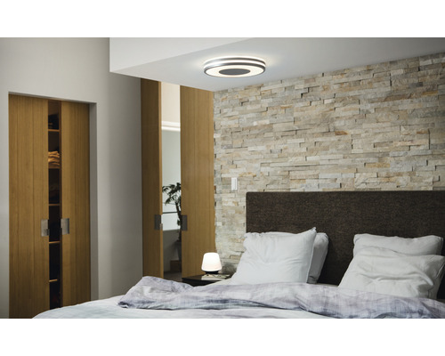 Slaapkamer met tweepersoonsbed, houten schuifdeuren, stenen muur en plafondlamp