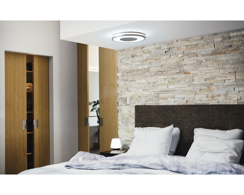 Slaapkamer met plafondlamp, stenen muur, bed en schuifdeuren