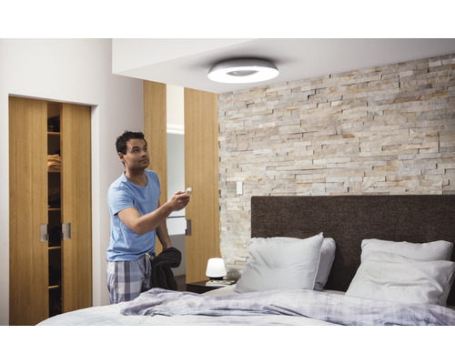 Man in slaapkamer met plafondlamp en afstandsbediening
