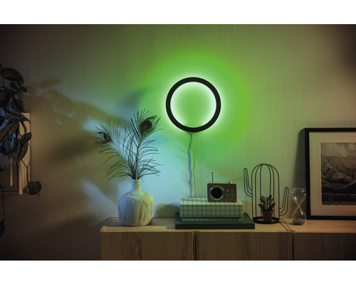 Woonkamer met cirkelvormige wandlamp en decoratieve elementen op een houten kast