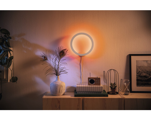Woonkamer met een ronde wandlamp en decoratieve elementen op een houten kast.