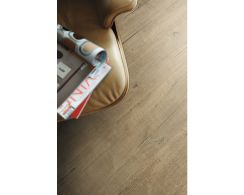 Close-up laminaatvloer met houtstructuur naast fauteuil en tijdschrift